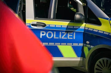 Deutsches Polizeifahrzeug mit gut sichtbarem Schriftzug „Polizei“ und unscharfem rotem Fahrzeug im Vordergrund. © mpix-foto