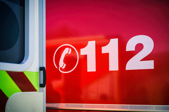 Notrufnummer 112 mit Telefonsymbol auf einem roten Feuerwehrfahrzeug.