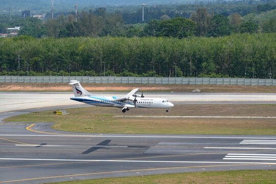 atr 72 turboprop commercial airplane descends onto the tarmac at a tropical airport with verdant trees in the distance, Thailand, 21 april 2026