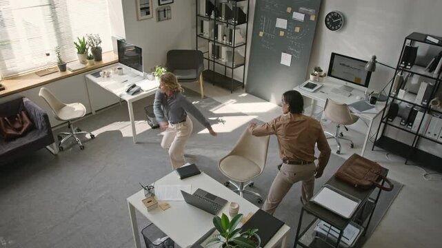 Multiethnic coworkers taking energetic active break, dancing and lunging during workday from high angle. Ideal for corporate wellness campaigns and employee health marketing videos