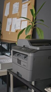 Vertical shot of modern multifunction printer standing in office workspace. Footage suitable for corporate paperwork, documentation workflow, printing technology concepts
