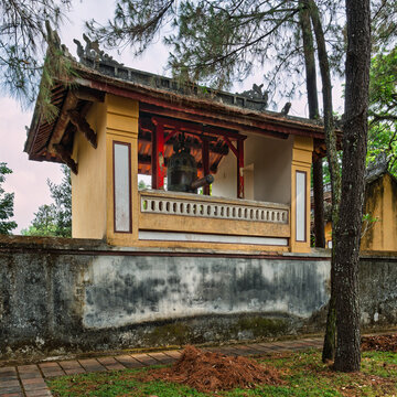 Ancient bell pavilion with a large bronze bell at the historic Thien Mu Pagoda in Hue, Vietnam