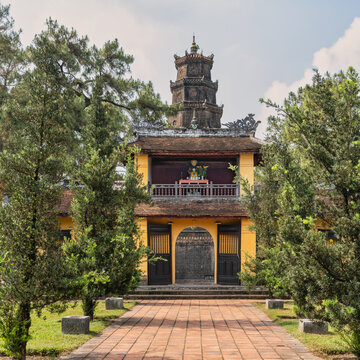 Entrance to the historic Thien Mu Pagoda with the iconic Phuoc Duyen Tower rising in the background, set within a lush garden landscape in Hue, Vietnam