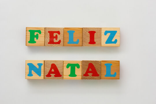 Colorful wooden alphabet blocks arranged in two rows to form the phrase Feliz Natal" in Portuguese means Merry Christmas