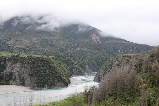 scenic alpine valley, turquoise-blue river, steep forested mountain slopes (wide-angle, panorama, low-hanging-cloud, mist, moving-train-view) 6559