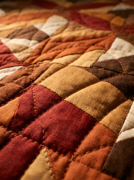 Close-up of a quilted patchwork blanket featuring autumn colors and detailed thread stitching. Warm, cozy textile background for fall home decor, crafts, and lifestyle designs
