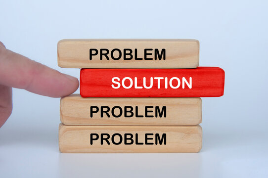 Hand moving a solution block toward wooden pieces representing progress and overcoming challenges.