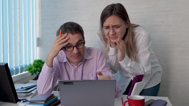 Stressed colleagues looking at a laptop screen with shock and frustration, the man throwing his hands up in despair. System failure, project crisis, and urgent workplace problems.