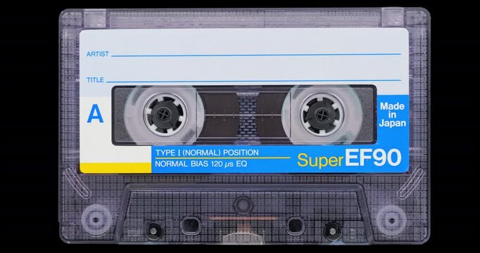 Analog audio cassette on black background. Transparent shell and labeled Super EF90 face remain still, giving nostalgic analog media calm, detailed look.