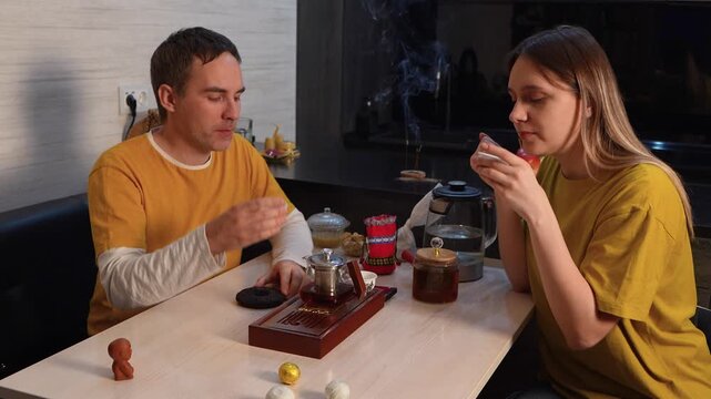 A couple drinking Chinese tea from traditional small tea cups at home, enjoying a peaceful tea ceremony and shared moment of relaxation.