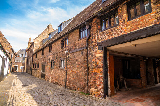 A view of historic brick buildings lining the cobbled street on Kings Staithe Lane in King's Lynn, Norfolk, England, in summertime
