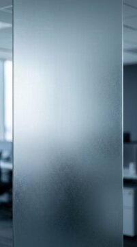 Glass partition reflects light inside a modern corporate office interior space.