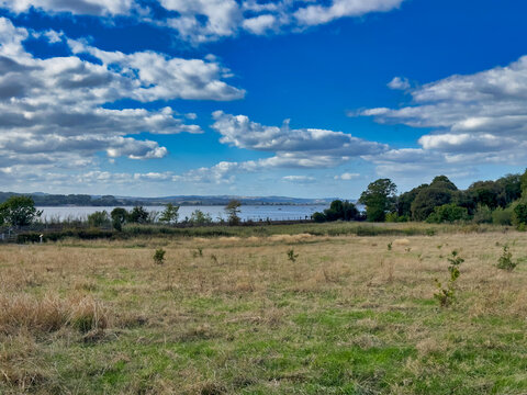 Scenic Coastal Field Landscape Overlooking Water Under a Dramatic Cloudy Sky