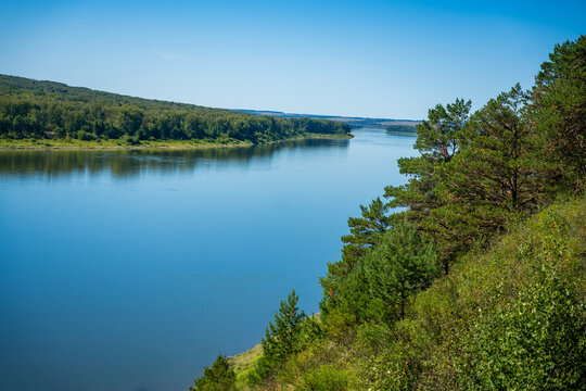 Scenic view of Tom River in Yashkinsky District near Tomskaya Pisanitsa, Siberia. Forested riverbanks and calm water form natural summer landscape