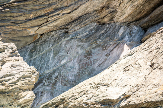 Ancient petroglyphs carved into rock at Tomskaya Pisanitsa in Siberia. Prehistoric rock art represents archaeological heritage and early human culture