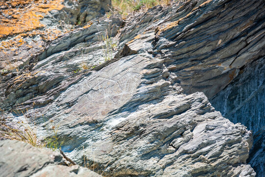 Ancient petroglyphs carved into rock at Tomskaya Pisanitsa in Siberia. Prehistoric rock art represents archaeological heritage and early human culture