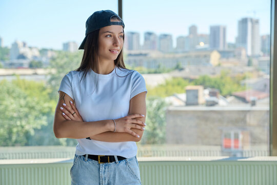 Young woman in backward cap standing arms crossed looking away