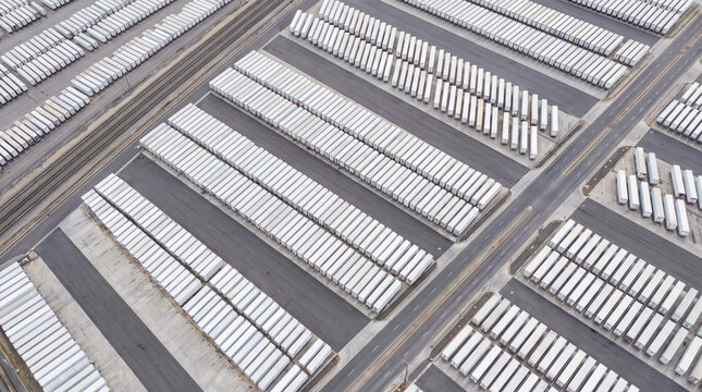 Numerous shipping containers and trailers parked in rows at a large transportation logistics hub from an aerial view