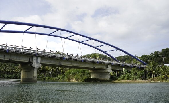 Blue Arch Bridge Over River with Green Tropical Nature Background