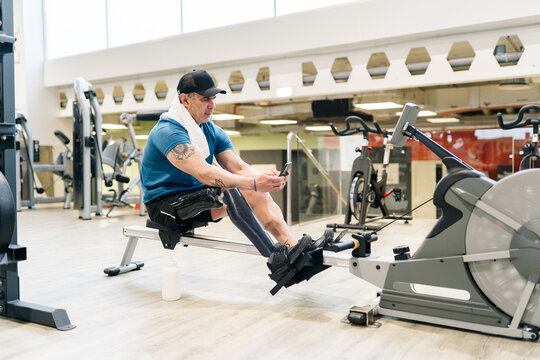 Male athlete with prosthesis using smartphone at gym