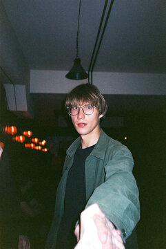 Young man extends hand at dimly lit venue