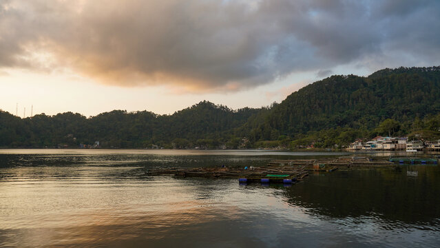 Floating Fish Farm on Lake with Mountain Backdrop at Sunset