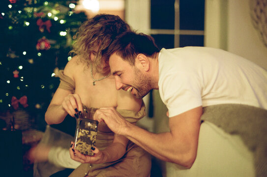 Couple Opening Christmas Gift Together at Home