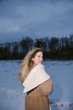 Woman in Beige Coat and Knitted Scarf in Snowy Winter Landscape