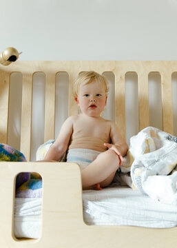 A small child sits in bed after sleeping