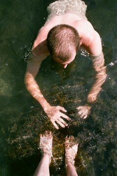 Man Reaching into Shallow Water from Above