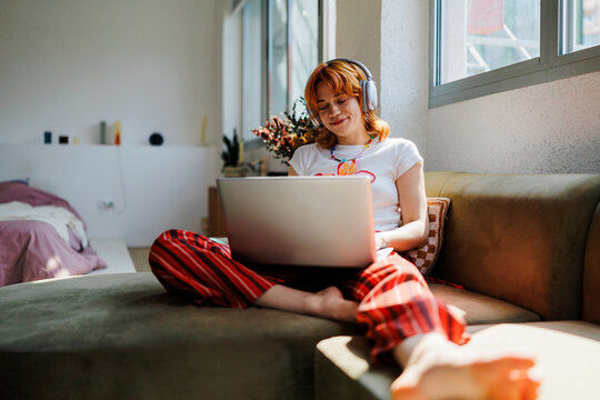 Woman enjoying laptop and music at home