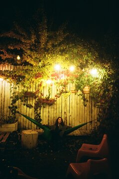 Woman Sitting in a Hammock Under String Lights