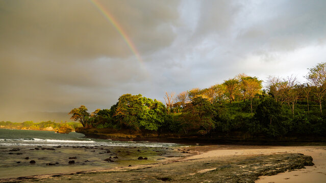 Rainbow Over Tropical Beach and Green Cliffs