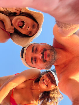POV Selfie of Three Friends Huddled Over Camera Against Blue Sky