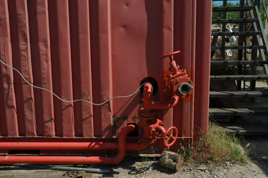 Industrial Valve on a Red Metal Wall