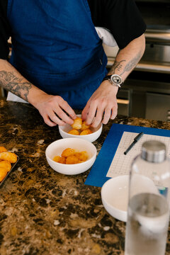 Close-up of a chef plating a haute cuisine dish in a modern kitchen.