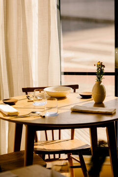 Gourmet pasta bowl on a wooden table in a sunny restaurant.