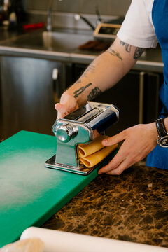 Close-up of anonymous chef using pasta machine in luxury restaurant