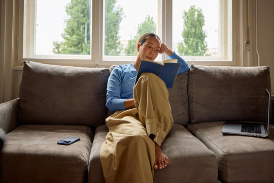 Woman reads a book on a couch