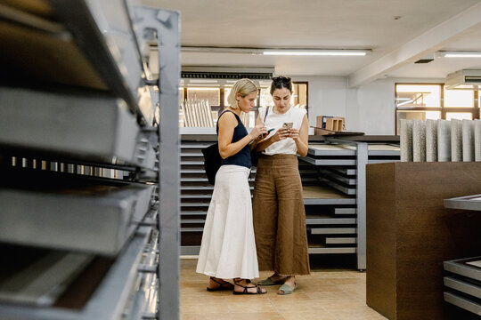 Architect and client checking phones in materials showroom