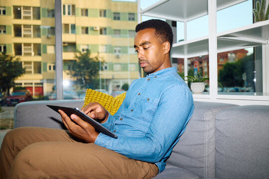 Relaxed man working on his tablet while seated on a sofa