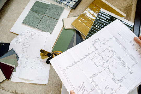 Anonymous Architect reviewing floor plan with material samples