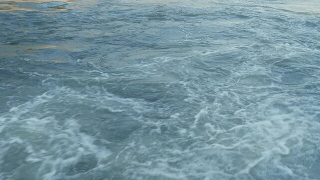 Fast-flowing water discharged through a river gate, creating turbulent currents, swirling eddies, and foamy waves, illustrating water flow, hydraulic management, river infrastructure, 