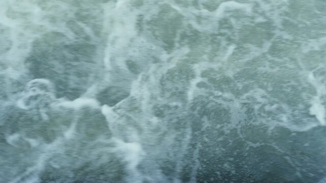 Fast-flowing water discharged through a river gate, creating turbulent currents, swirling eddies, and foamy waves, illustrating water flow, hydraulic management, river infrastructure,