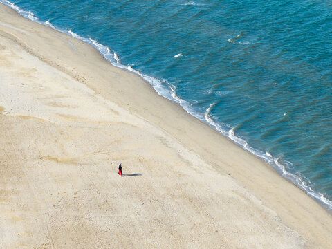 Two distant people alone on a vast sandy beach with gentle waves