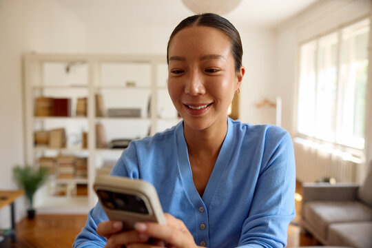 Beautiful woman texts on her phone at home