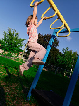Young girl swinging across monkey bars