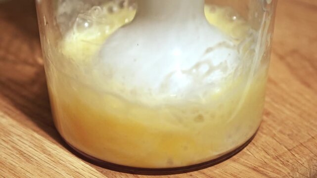 A transparent container holds an egg yolk separated from the egg white. The white plastic yolk separator is positioned above the yolk, allowing the clear egg white to drain through its slots and.