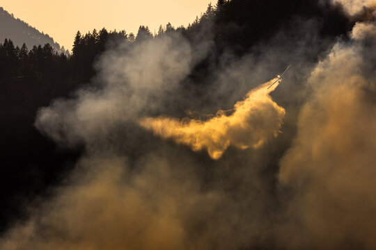 Airplane drops water on a wildfire from above.