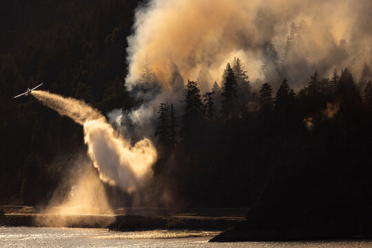 Airplane drops water on a wildfire from above.